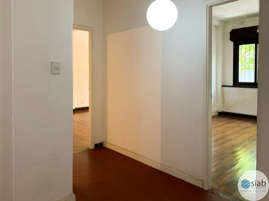 # Property Image Description
This is a hallway or corridor space featuring clean white walls, a round ceiling light fixture, and dark wood flooring. The hallway provides access to multiple rooms visible through open doorways on both sides, with natural light entering from windows in the adjacent spaces. The area is in good condition with modern finishes and neutral décor.
WATERMARK: SIAB Inversiones